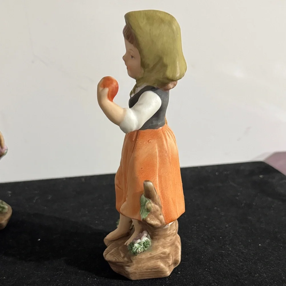 vintage hand-painted porcelain figurines of a boy and girl carrying baskets.